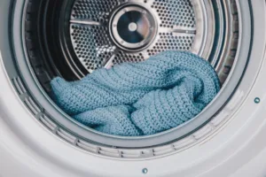 Close-Up View of a Cozy Blue Knitted Blanket Inside a Modern Washing Machine Drum or Clothes Dryer, Highlighting Soft Textures and Efficient Laundry Care