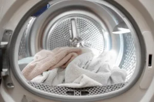 View of the tumble dryer or washing machine with the door open and a towel inside
